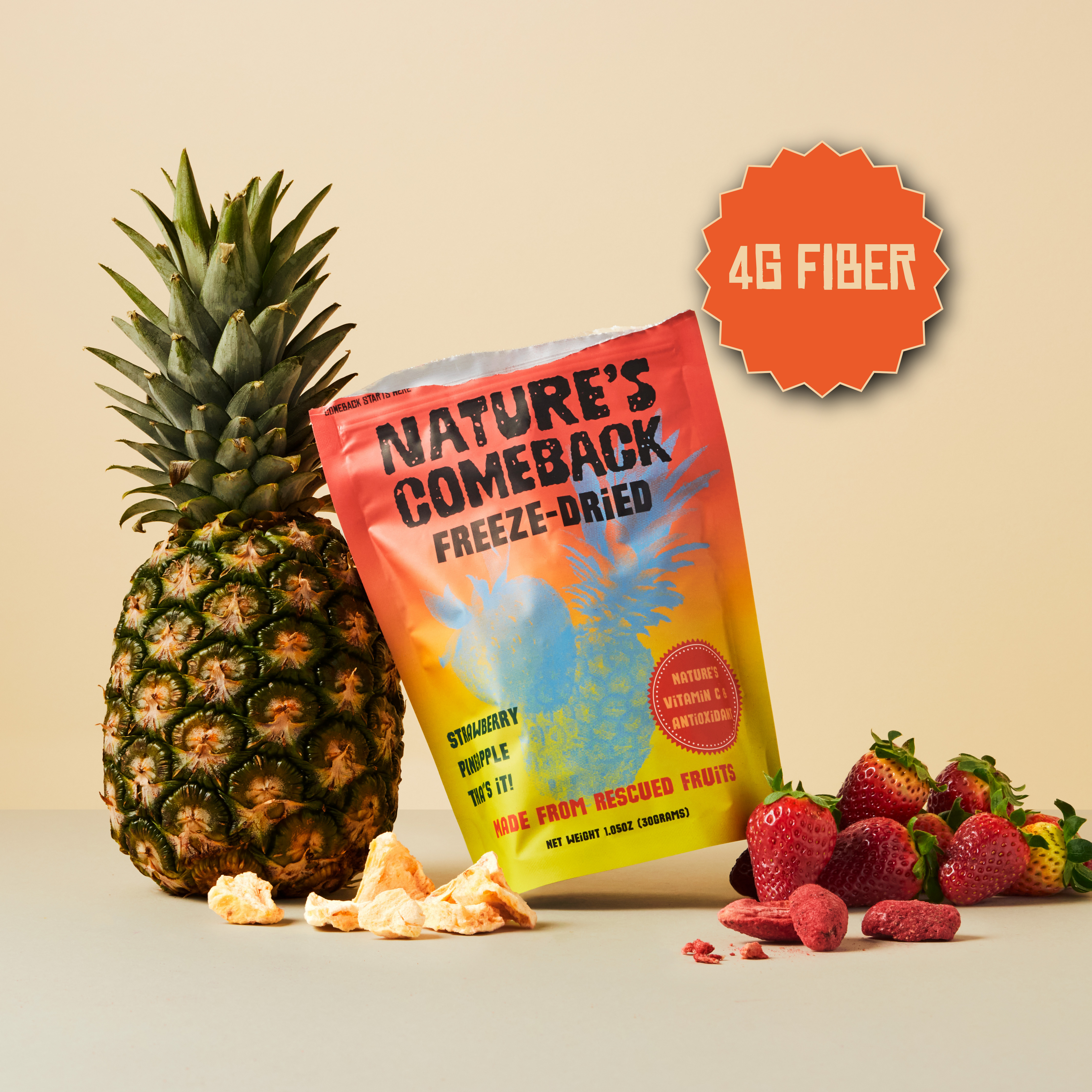 A stand-up pouch of Nature's Comeback Freeze-Dried fruit snacks is styled with a whole pineapple, loose dried pineapple pieces, and fresh strawberries on a warm beige studio background. An orange starburst badge in the top right reads '4G FIBER'.