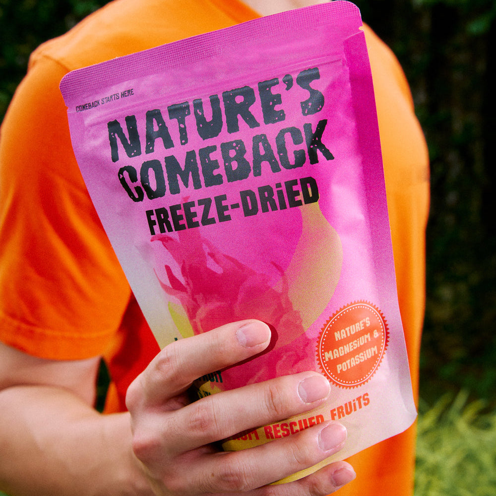 Person holding a pink 'Nature's Comeback Freeze-Dried' package with a blurred green background